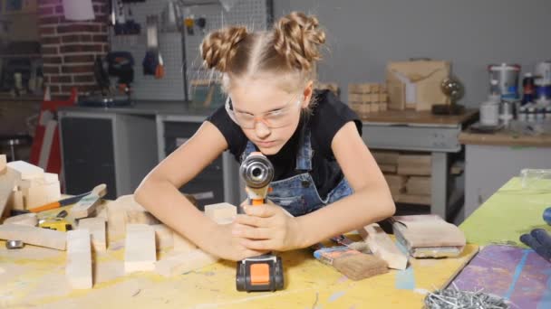 Petite fille de 10 ans et une perceuse dans les mains. Au ralenti. Jeune jolie fille constructeur tient foret dans ses mains, allumer, sourire, conception de bâtiment. hd 