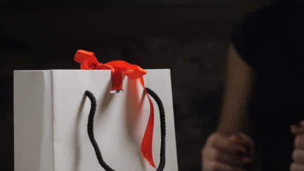 Άνοιγμα παρούσα. Κοντινό πλάνο. γυναικεία δάχτυλα Ανοίξτε ένα δώρο που κρατά το κουτί, λύστε κόκκινη κορδέλα και να πάρουν ένα μικρό κουτί με ένα δαχτυλίδι στο εσωτερικό. έκπληξη για τα κορίτσια. HD — Αρχείο Βίντεο