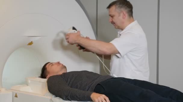 Computer tomography concept. Health concept. Person gets scanned by magnetic resonance imaging scanner in modern hospital.Male radiology specialist in white coat preparing patient for CT MRI procedure — Stock Video