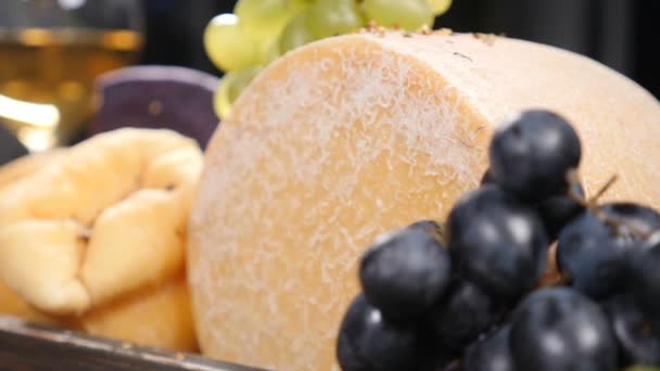 Set de queso duro bellamente puesto en caja de madera decorada con uvas. Especias que caen sobre la composición en cámara lenta. Sala de exposición del restaurante. Arte de la comida. hd — Vídeo de stock