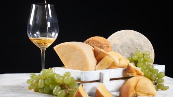 赤ワインはチーズ プレートの背景にグラスに注がれています。チーズ愛好家。木製の箱のそばでブドウの美味しいハードチーズ。hd — ストック動画