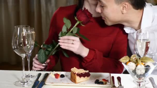 Assuntos amorosos. 14 de Fevereiro. Jovem mulher atraente segurando uma rosa vermelha. Cheiros de homem. Casal jovem no encontro no restaurante. hd — Vídeo de Stock