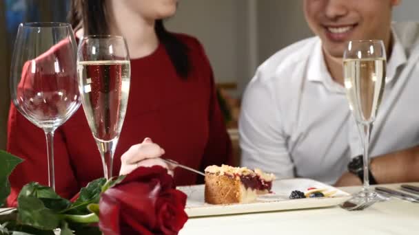 Romántico y amoroso. pareja joven en una cita. Una mujer alimenta a su hombre con un delicioso postre. Pareja riéndose en un restaurante. Copas de champán en la mesa. hd — Vídeo de stock