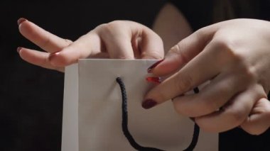 Mevcut kaydırma. Kırmızı kurdele bağlama parmaklar mevcut kutusunda yay. Kadın Eller masanın üstüne mevcut ambalaj closeup çekim. Noel hediyesi, doğum günü hediyesi, yılbaşı hediyesi konsept yay. HD