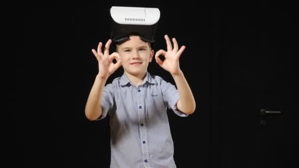 Future science concept. Contemporary childhood concept. .Young handsome boy uses virtual reality glasses and shows thumb up to the camera with blackground., closeup. hd — Stock Video