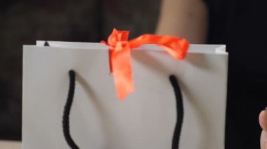 Karanlık görüntü. Romantik bir atmosfer. Mevcut açılış. Yakın çekim. parmaklar bir hediye kutusu tutarak açın, kırmızı kurdele çöz ve küçük bir kutu içinde bir halka ile dışarı çıkar. Kızlar için bir sürpriz. HD