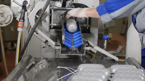 Magazzino alimentare. Le mani dei lavoratori gestiscono una linea di produzione automatizzata che produce salsicce. La salsiccia dopo aver attraversato la linea di produzione viene presa dal lavoratore e messa sul tavolo. vicino. Girato in 4k — Video Stock