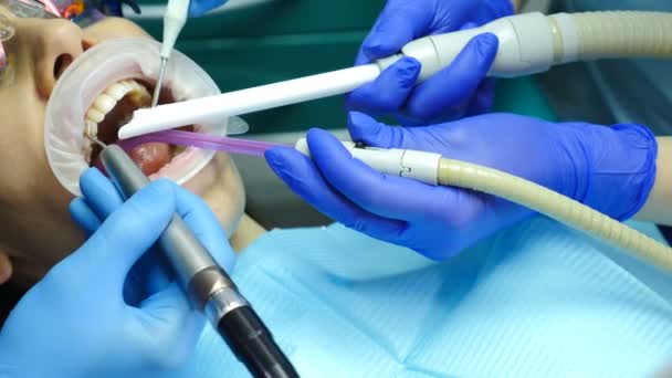 Οδοντιατρική κλινική έννοια. Βολή closeup της οδοντίατρος θεραπεία θηλυκός ασθενής με μια expander στο στόμα. Στο σύγχρονο οδοντιατρείο. Ορθοδοντικός συνεργάζεται με βοηθός. 4k — Αρχείο Βίντεο