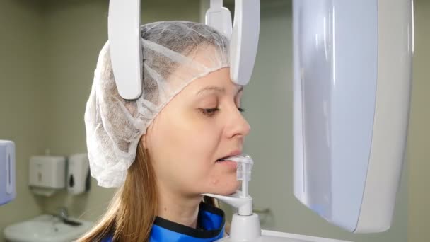 Procedimiento médico en ortopantomografía 3d. Tomando una radiografía digital panorámica de los dientes de un paciente. Mujer joven sometida a examen de rayos X panorámico, equipo radiográfico profesional en clínica dental moderna — Vídeo de stock