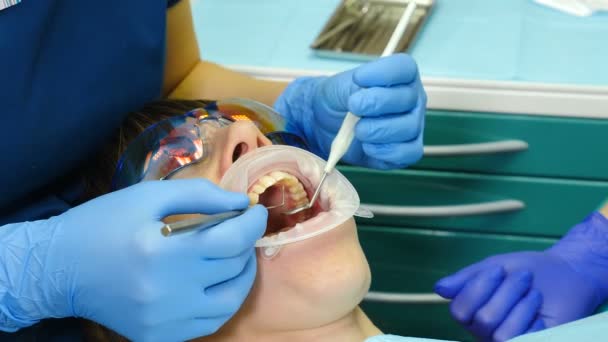 Ärztin behandelt Patientin in ihrem Kabinett. Nahaufnahme einer jungen Frau mit einem Expander im Mund in der Zahnarztpraxis. Zahnarzt mit Werkzeugen, Vakuum, Bohrer, Geräte, Instrumente in der Klinik. 4k — Stockvideo