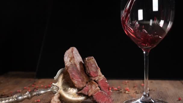 Taze pişmiş biftek kahverengi ahşap tahta üzerinde yalan close-up. Ağır çekimde dökülen kırmızı şarap. Vintage çatal üzerinde et. HD — Stok video