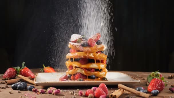 Koch streut Zuckerpulver auf leckeren Pfannkuchen, Zeitlupe. Mehl, das auf Pfannkuchen gesiebt wird. Nahaufnahme-Pfannkuchen stapeln sich auf einem Teller, der mit Preiselbeeren dekoriert und mit Puderzucker bestäubt wird — Stockvideo