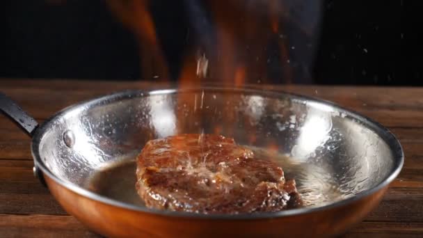 Chef profesional cocina carne inflamable. Cocinar prende fuego a la carne en la sartén, cocinar con fuego, asar y asar a la parrilla, fuego en cámara lenta 180 cuadros por segundo. En cámara lenta. hd — Vídeos de Stock