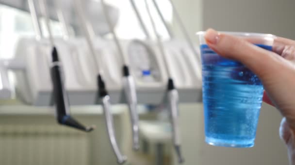 Modern dental clinic. Medical equipment in disfocus with plastic cup with blue aseptic liquid in front. 4k — Stock Video