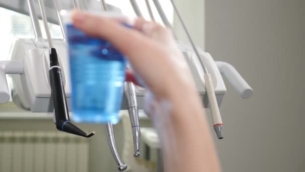 Modern dental clinic. Medical equipment in disfocus with plastic cup with blue aseptic liquid in front. 4k — Stock Video