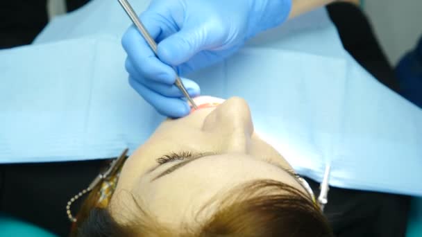 Ärztin behandelt Patientin in ihrem Kabinett. Nahaufnahme einer jungen Frau in einer Zahnarztpraxis. Zahnarzt mit Spiegel und anderen Instrumenten in der Klinik. 4k — Stockvideo