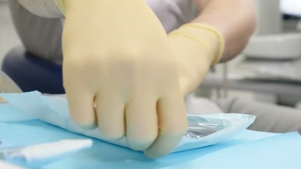 Αρσενικό οδοντίατρος ανοίγει άσηπτη εργαλεία. οδοντίατρος αποσυμπιέζει στείρα Οδοντιατρικά εργαλεία. 4k — Αρχείο Βίντεο