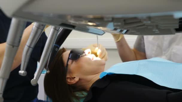 Tiro de herramientas de dentista en el primer plan y desenfoque paciente sentado en la silla de dentista en el fondo. médico trata a la paciente femenina en el gabinete dental. 4k — Vídeos de Stock