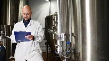 Bira kavramı. Bira fabrikası, Panodaki yazma özenli bakım işçisi. Bira çalışan ekipman denetler. İçecek ekipmanları Fabrikası'nda kontrol laboratuar önlüğünü bira fabrikası işçisi. 4k