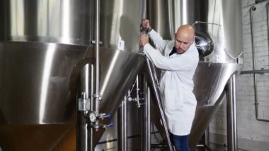 Bira kavramı. Bira fabrikası, Panodaki yazma özenli bakım işçisi. Bira çalışan ekipman denetler. İçecek ekipmanları Fabrikası'nda kontrol laboratuar önlüğünü bira fabrikası işçisi. 4k