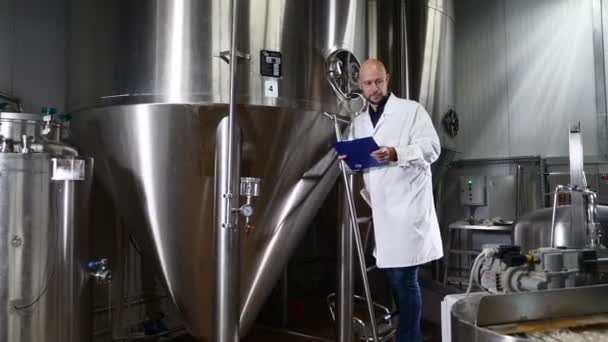 Bier maken bij brouwerij. De werknemer van de brouwerij wordt de apparatuur gecontroleerd. Onderhoud werknemer operationele controle machine op bier fabriek. 4k — Stockvideo