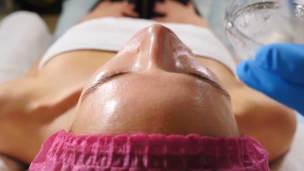 Cosmetolog Aplicarea transparentă a cremei faciale pe frunte cu o perie. Privire de sus împușcat pe procedura de frumusețe în salonul modern. De aproape. hd — Videoclip de stoc