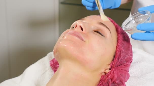 抗衰老面部与面膜霜按摩在妇女脸上。透明液体与胶原蛋白, 美容维生素和天然营养, 以提高皱纹在美容师诊所水疗医院。高清 — 图库视频影像