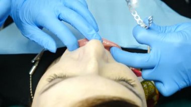 Diş kliniği konsepti. Modern diş hekimleri ofisinde Tmj muayene. 30'lu yaşlarda bir kadın çene ağrısı yaşıyor. Doktorlar kadın müşteriyi Jaw ortak soruşturması için hazırlıyorlar. 4k