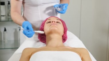 Cilt bakımı konsepti. güzellik salonunda genç kadın. Güzellik Uzmanı Kadın müşteriye yüz maskesi uyguluyor. Spa. Yüz maskesi alan kadın. Yakından kapatın. Hd