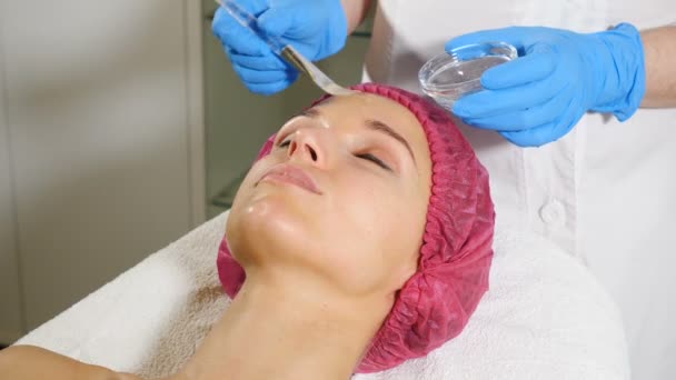 Trattamento termale. Giovane donna attraente al salone di bellezza. Estetista Applicando maschera facciale al cliente femminile. Terapia termale. giovane signora che riceve maschera facciale. Chiudete. hd — Video Stock