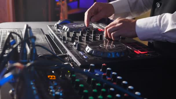 DJの手のクローズアップは、ターンテーブルの音楽機器上の音楽ミキシングやスクラッチを再生します。男性ディスクジョッキーによって再生されているライトとコントロールを備えたプロの音楽機器。Hd — ストック動画