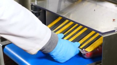 Bitmiş ürünlerin ambalaj hattı. Gıda paketleme makinesi. Et endüstrisi. Bir çeşit gıda işleme. Pelmeni ve ravioli üretim hattı. Otomatik konveyör. Eller hazır paketleri alıyor. 4k