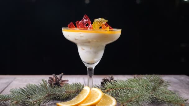 Top Visa på läckra dessert i glasskål på trä ombord dekorerad med Gran-trädgrenar och skivor av citron. Isolerad på svart bakgrund. Chef hand sätter bit marmelad ovanpå. Hd — Stockvideo