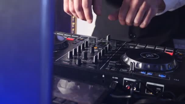 DJ atrás do console, no palco, misturando faixas em dança atmosférica festa strobing e luzes piscando. Close up de DJ mãos tocando música. Close-up de mesa de controlador de misturador Dj em festa discoteca — Vídeo de Stock