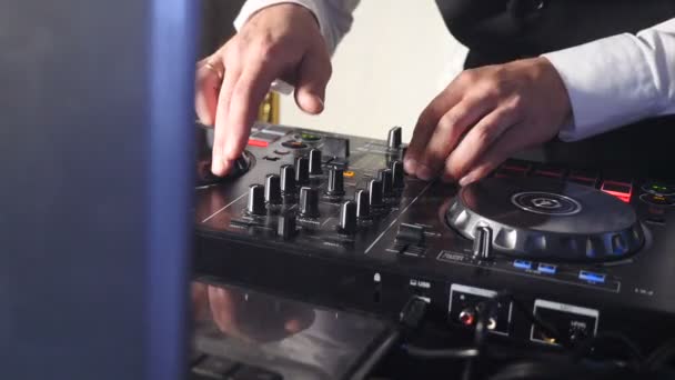 DJ πίσω από την κονσόλα, στη σκηνή, ανάμειξη κομματιών σε ατμοσφαιρικούς χορούς πάρτι και φώτα που αναβοσβήνουν. Κλείστε τα χέρια του DJ παίζοντας μουσική. Κοντινό μέρος του γραφείου ελέγχου Μείκτης DJ στο νυχτερινό κλαμπ ντίσκο πάρτι — Αρχείο Βίντεο
