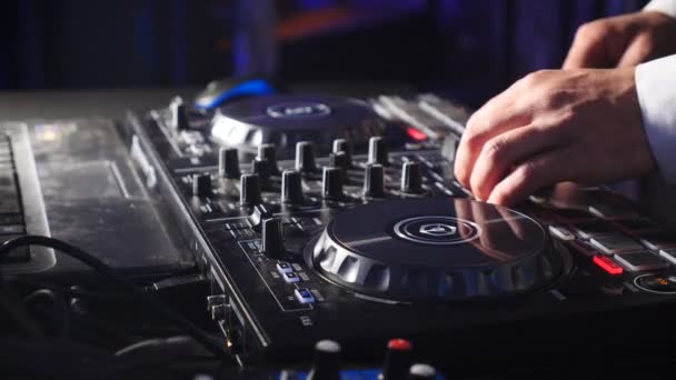 DJ atrás do console, no palco, misturando faixas em dança atmosférica festa strobing e luzes piscando. Close up de DJ mãos tocando música. Close-up de mesa de controlador de misturador Dj em festa discoteca — Vídeo de Stock