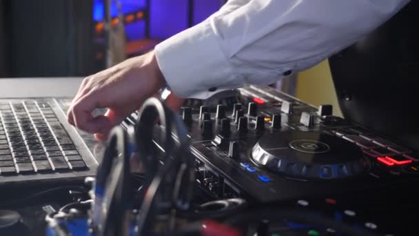 DJ atrás do console, no palco, misturando faixas em dança atmosférica festa strobing e luzes piscando. Close up de DJ mãos tocando música. Close-up de mesa de controlador de misturador Dj em festa discoteca — Vídeo de Stock