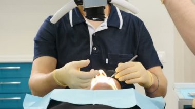 Ofisinde ki taNınmaz bir dişçi. Erkek doktor kadın hastanın dişlerini ve çenelerini inceler. Hastayla çalışan ortodontistin portresi. 4k