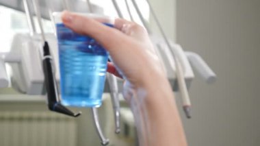 Modern diş kliniğinde diş hekimi araçları seti. ayna, forceps kavisli, kaşif kavisli. Diş Hijyeni ve Sağlık kavramsal görüntü. İlk planda mavi sıvı ile plastik cam Shot. 4k