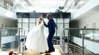 Esmer gelin ve yakışıklı damat dans komik dans otel lobisinde. Güzel, yeni evli bir çift. Neşeli şık yeni evliler mutlu dans ederken eğleniyoruz. Hd
