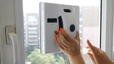 Temiz hizmet. Dişi el güç açma. Pencere temizliği modern yolu. Robotik cam yıkayıcı hareket ve özel daire penceresinde döner. Pencerede çalışan otomatik cam yıkayıcı