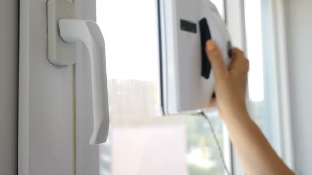 깨끗한 서비스. 여성 손 전원을 켜고 있습니다. 창문 청소의 현대적인 방법. 개인 아파트에서 창문에서 움직이는 로봇 유리 와셔. 창에서 작동하는 자동 유리 와셔 — 비디오