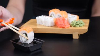 Japon restoranı deniz ürünleri menüsü. Deniz ürünleri. Sağlıklı beslenme, beslenme, diyet kavramı. Yemek videosu. Chopsticks dunks ile kadın el closeup shot şık soya sosu içine set Sushi koydu. damla ve