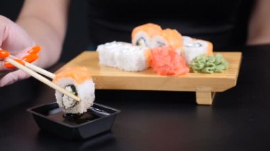 Yavaş hareket edilen gıda görüntüleri. Japon restoranı deniz ürünleri menüsü. Sağlıklı beslenme, beslenme, diyet kavramı. Chopsticks dunks ile kadın el closeup shot şık soya sosu içine set Sushi koydu. damla ve