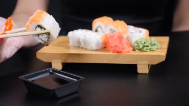 Yavaş hareket edilen gıda görüntüleri. Japon restoranı deniz ürünleri menüsü. Sağlıklı beslenme, beslenme, diyet kavramı. Chopsticks dunks ile kadın el closeup shot şık soya sosu içine set Sushi koydu. damla ve
