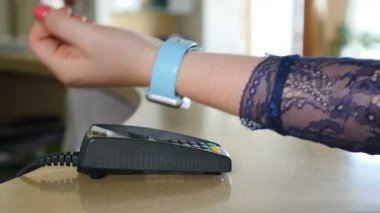 Terminalde temassız akıllı saat ile Nfc teknolojisi ile ödeme yapan bir kadın Müşteri elinin yakın çekim çekimi. 4k