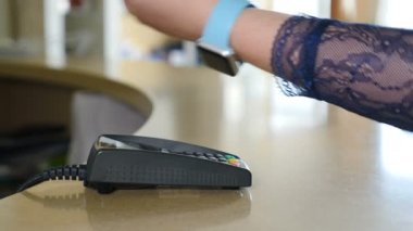 Kız akıllı saat kullanarak ödeme. Yakından kapatın. Terminal ve Akıllı Saat Ödeme. Kadın müşteri saat ile ödüyor. 4k