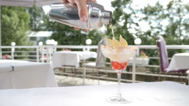 Mat video i slow motion. Process för servering av sommarfrukt cocktail på öppen restaurangterrass. Bartender hälla alkohol dryck i ett glas närbild. Hd — Stockvideo