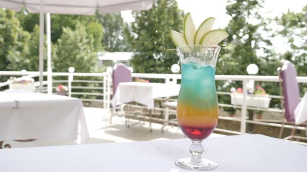 Slowmotion shot of bartender in outdoor restaurant terrace serving a summer cocktail with a slice of orange and berries. cubos de gelo caindo em um copo. Vídeo de comida. conceito de nutrição e bebida. hd — Vídeo de Stock