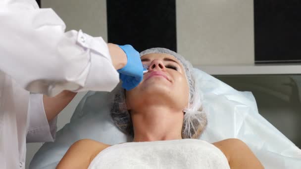 Junge Frau in moderner Schönheitsklinik bekommt Injektion zur Faltenkorrektur im Gesicht. nicht-chirurgische Korrektur der Nasenform. Injektion mit Nadelspritze. 4k — Stockvideo